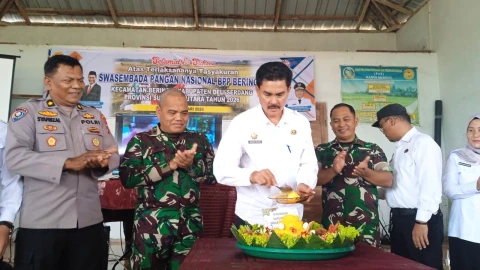 Drs Hendra Wijaya melakukan pemotongan tumpeng sebagai bentuk rasa syukur atas keberhasilan panen raya dan pencapaian swasembada pangan nasional di P4S Karya Mandiri, Desa Sidodadi Ramunia, Kecamatan Beringin, Rabu (7/1/2026).