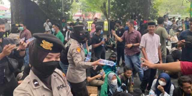 Polwan membagikan air mineral pada mahasiswa yang berunjukrasa, Rabu (13/4).