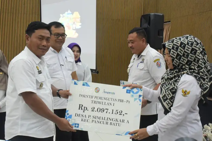 dr H Asri Ludin Tambunan bersama Wakil Bupati Lom Lom Suwondo SS dan Ketua TP PKK Kabupaten Deli Serdang Ny Jelita Asri Ludin Tambunan menyerahkan insentif pemungutan PBB-P2 Triwulan I kepada camat, kepala desa hingga kepala dusun secara simbolis di Central Hall Pancur Batu, Rabu (13/5/2026).