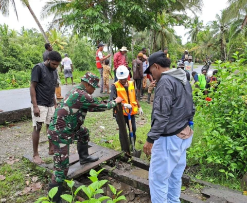 Sertu Yulius Nampe bersama warga melaksanakan kerja bakti membersihkan drainase
