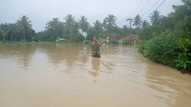 Babinsa setempat menunjukkan tingginya banjir di wilayah Sergai 