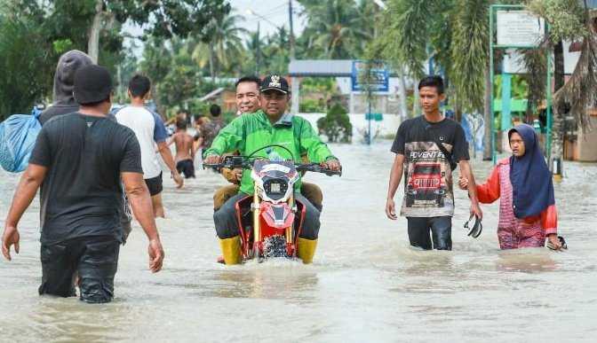 Bupati Sergai H. Darma Wijaya menunggangi motor trail meninjau lokasi banjir di Kecamatan Sei Rampah dan Tanjung Beringin&nbsp; berboncengan dengan Kadis PUPR Johan Sinaga.